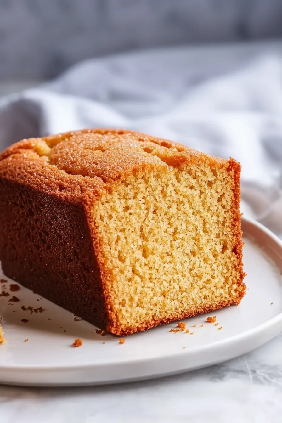 Golden-brown cake loaf resting on a plate, ready to serve.
