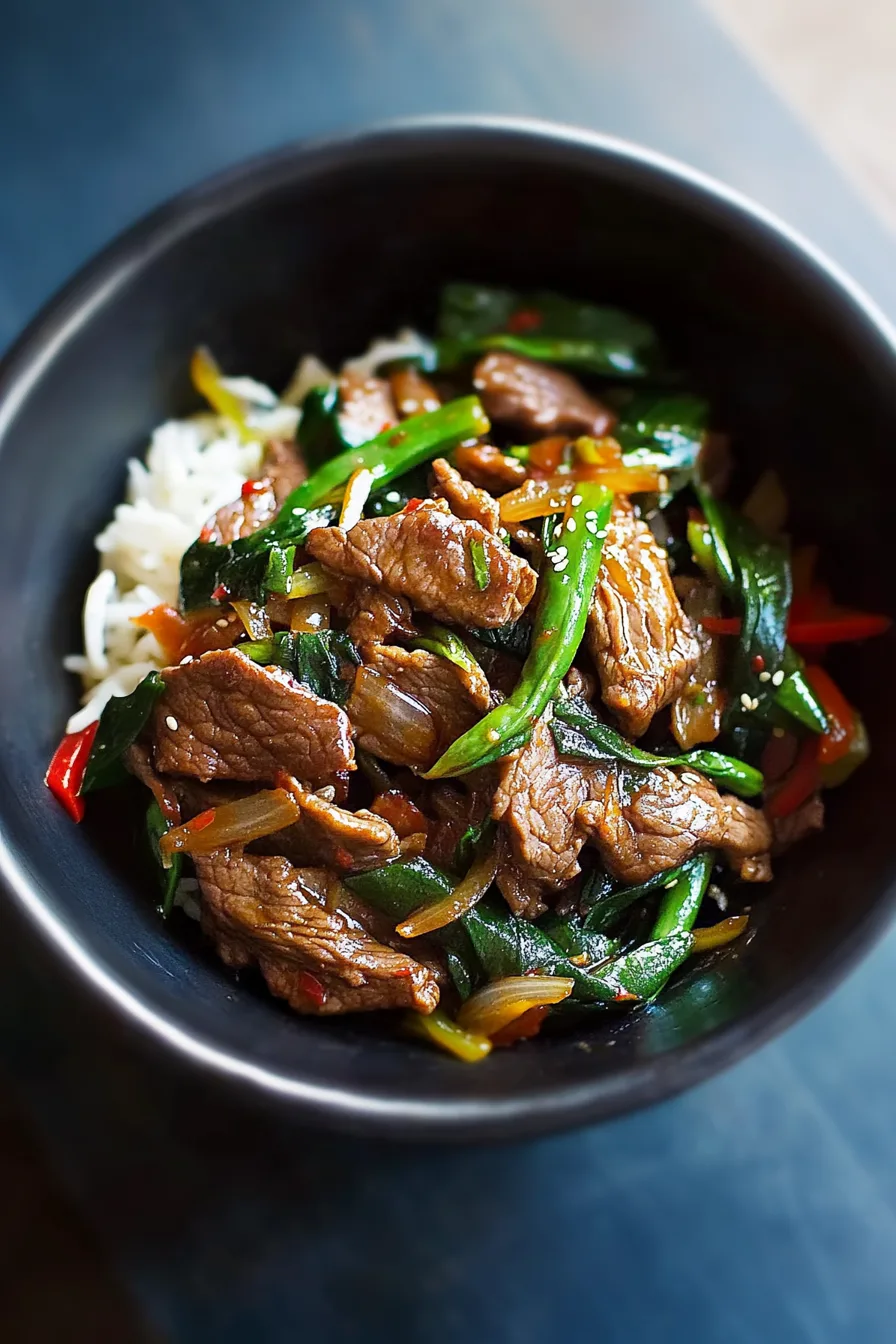 A bowl filled with stir-fried beef and vegetables, garnished lightly for serving.
