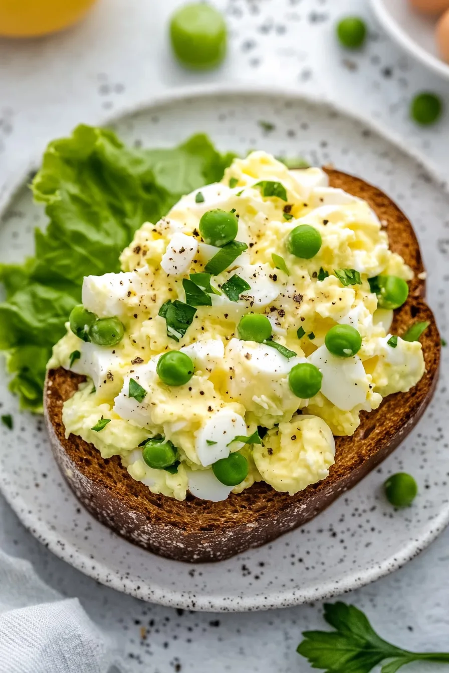 Hearty egg salad toast on a speckled plate with lettuce on the side.