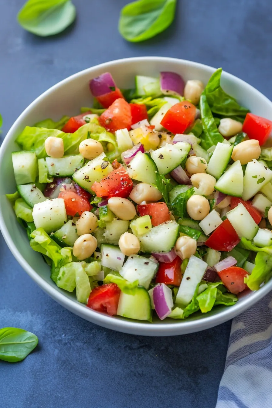 Plated greens with chunks of cheese, tomatoes, and cucumbers arranged in a bright mix.