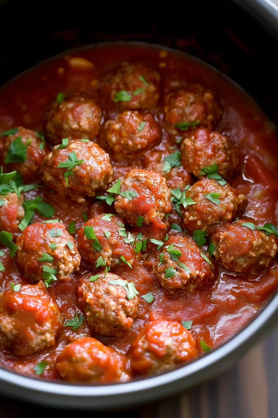 Saucy meatballs with visible herbs and onions in a deep pan.