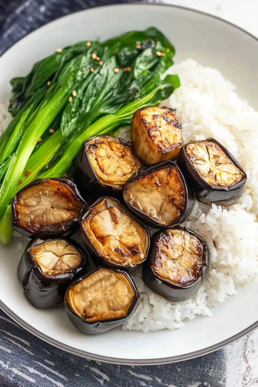 Roasted eggplant halves brushed with a glossy brown glaze and sprinkled with sesame seeds.