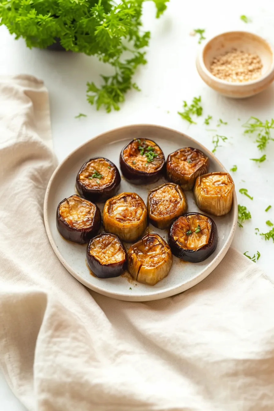 Grilled eggplant served on a plate with sesame seeds and fresh herbs on top.