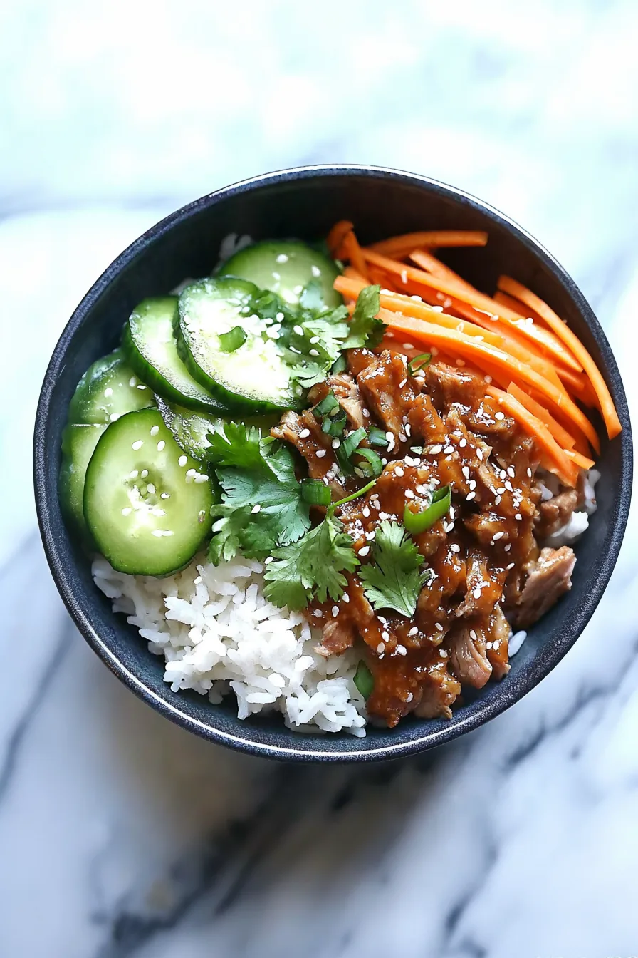 Colorful rice bowl featuring marinated pork, crisp vegetables, and fresh greens served together.