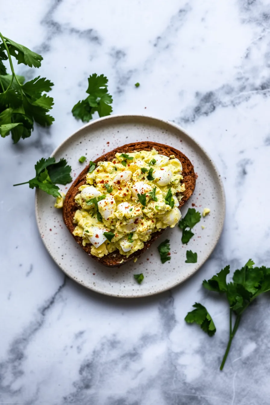 Final plated egg salad showing diced eggs, creamy dressing, and garnished green onions.