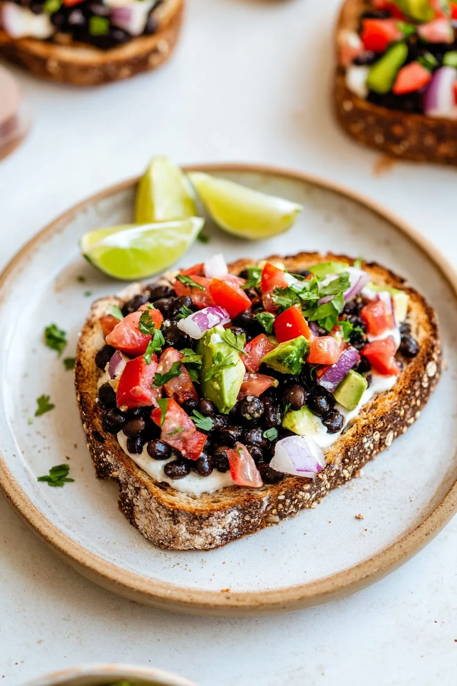 Savory toast arranged on a plate with bright, fresh toppings and wedges of lime for squeezing.