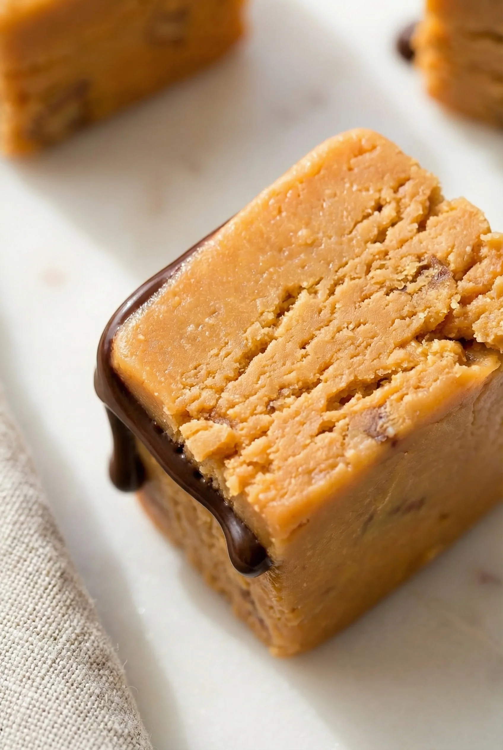 Close-up of creamy caramel-colored fudge pieces with chocolate on top.