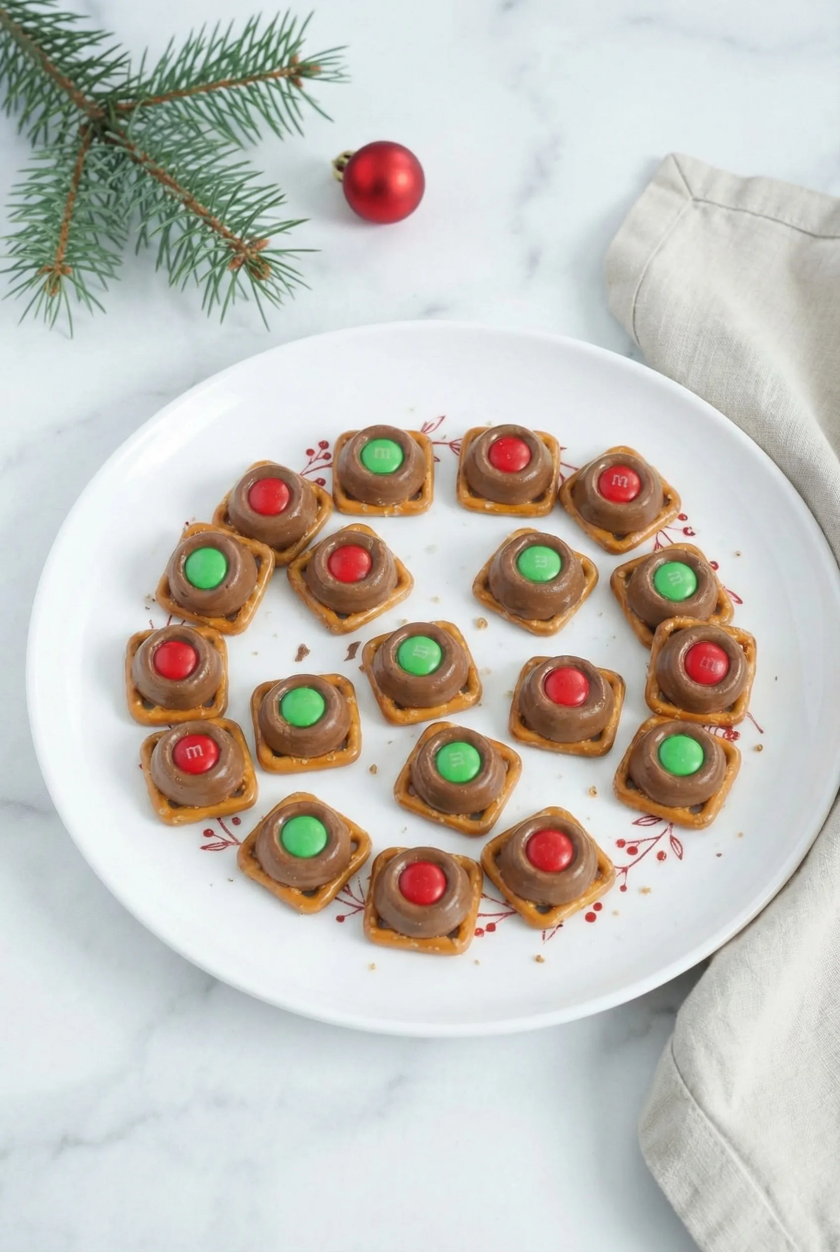 A tray of glossy, chocolate-covered caramel pieces melted onto pretzels and finished with holiday-colored candies.