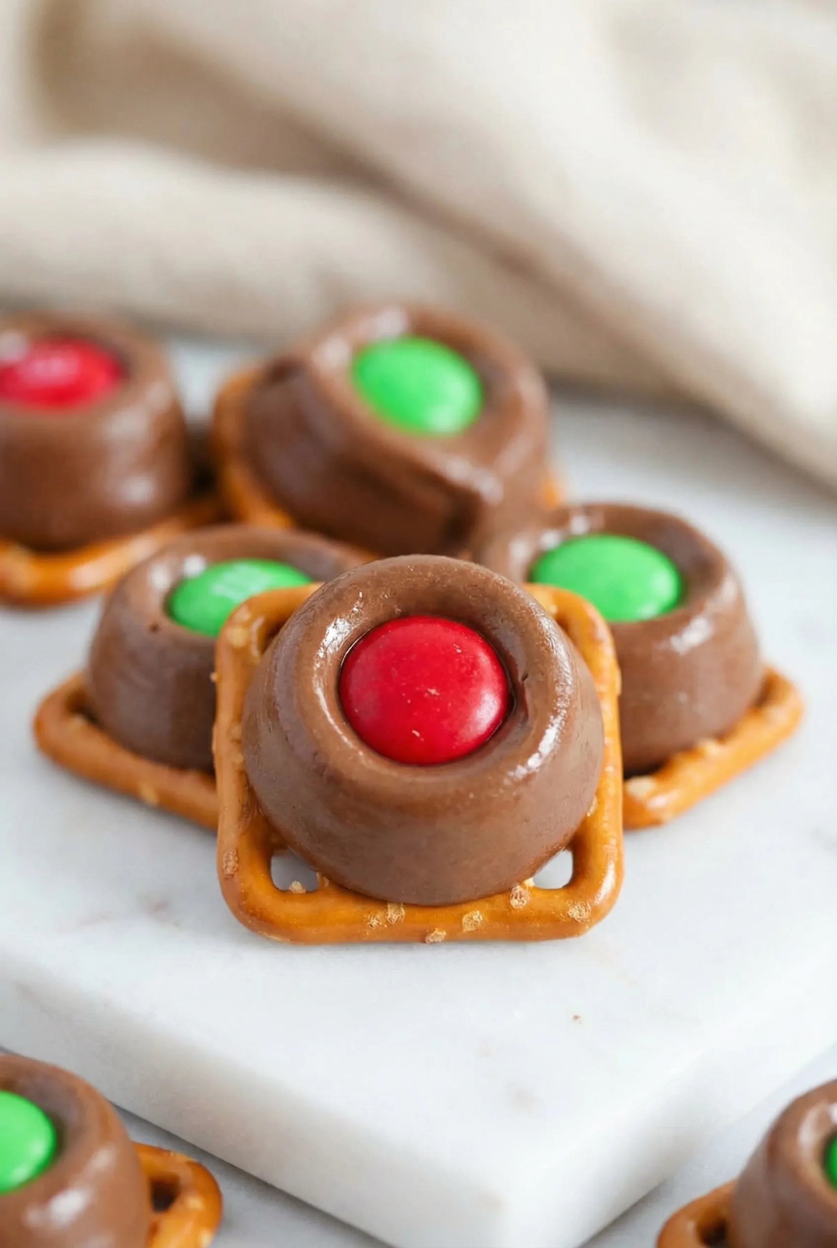 A neatly stacked batch of pretzel bites with melted chocolate caramel centers and bright candy toppings.