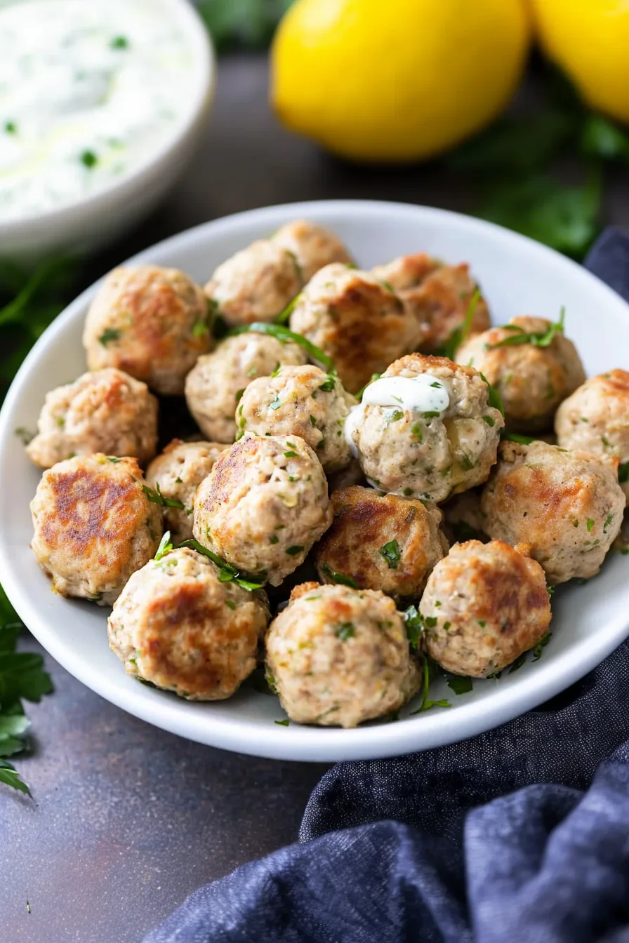 Freshly cooked meatballs with a crisp outer crust and lemon in the background.