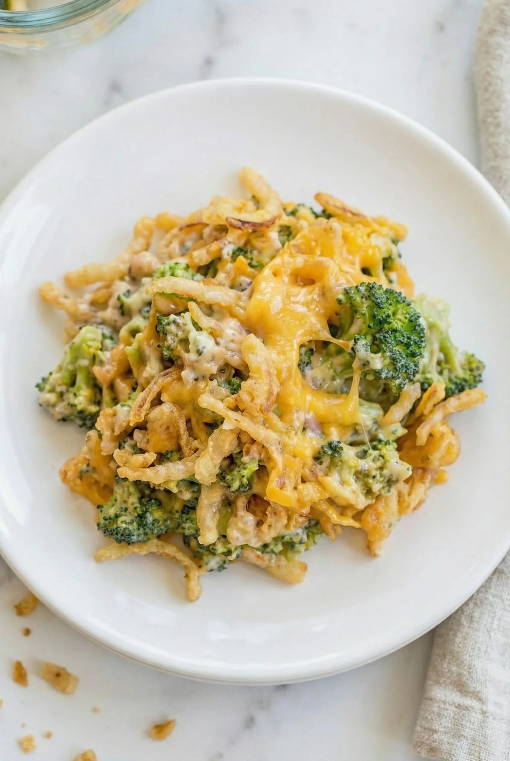 Close-up of a cheesy, browned casserole surface with visible broccoli pieces.