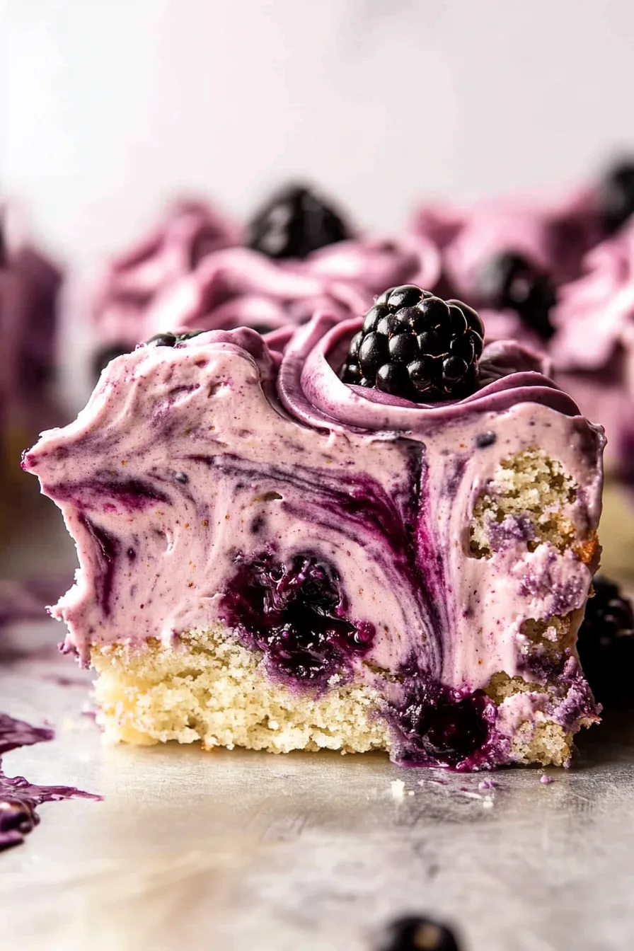 Close-up of marbled mousse topping with deep violet hues and glossy blackberry garnish.