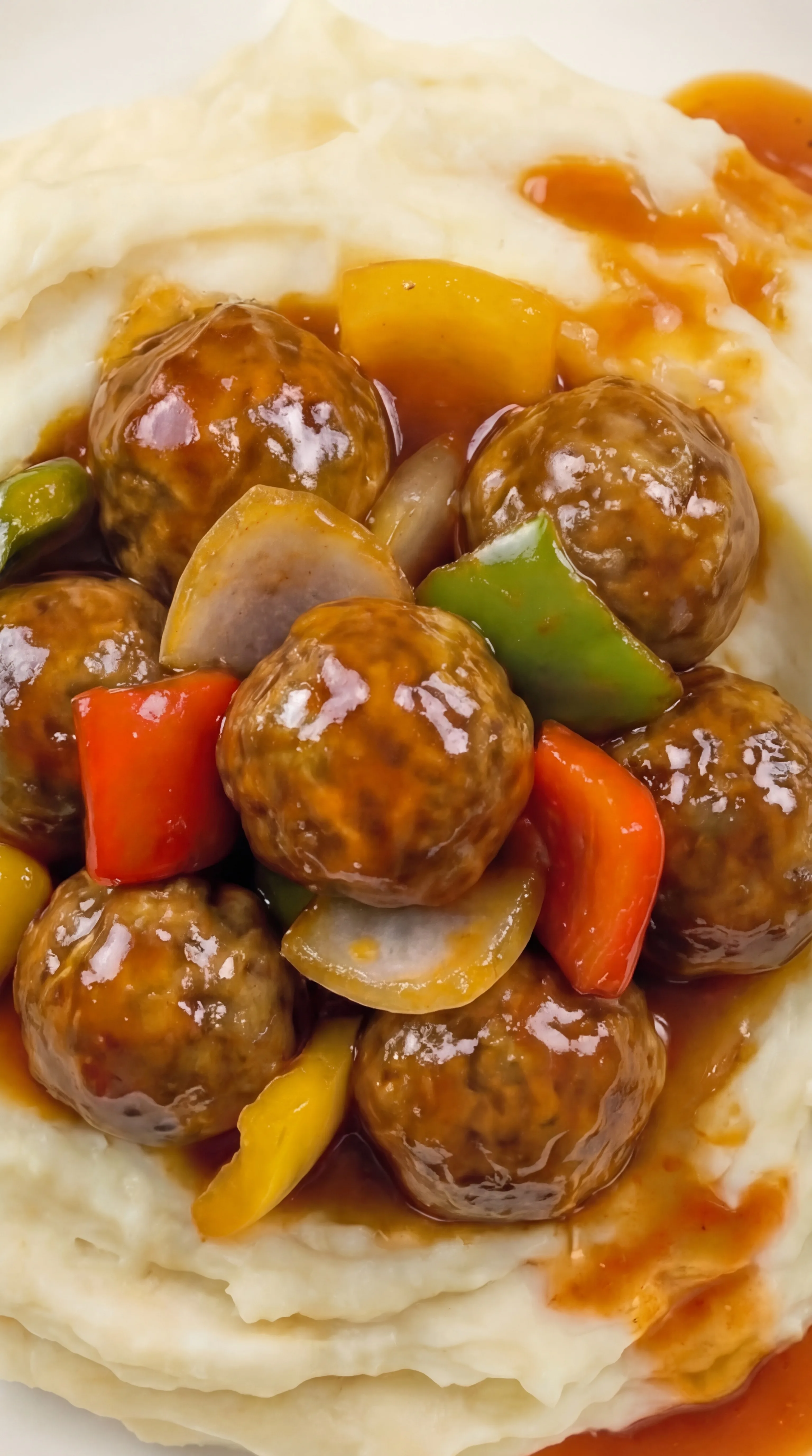 tender meatballs in glossy sweet and sour sauce on smooth mashed potatoes