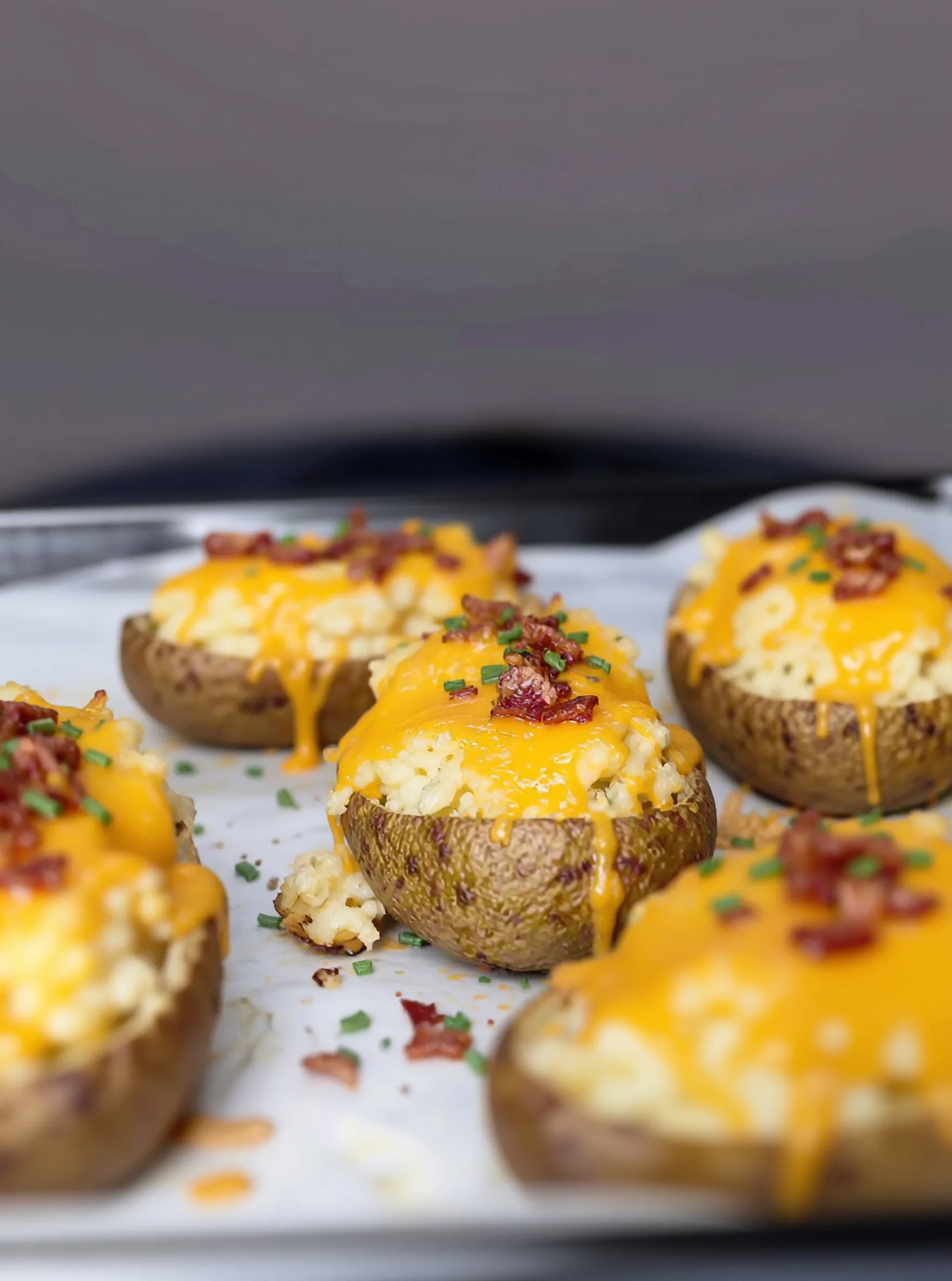 golden baked potato halves topped with melted cheddar cheese bacon bits and fresh chives