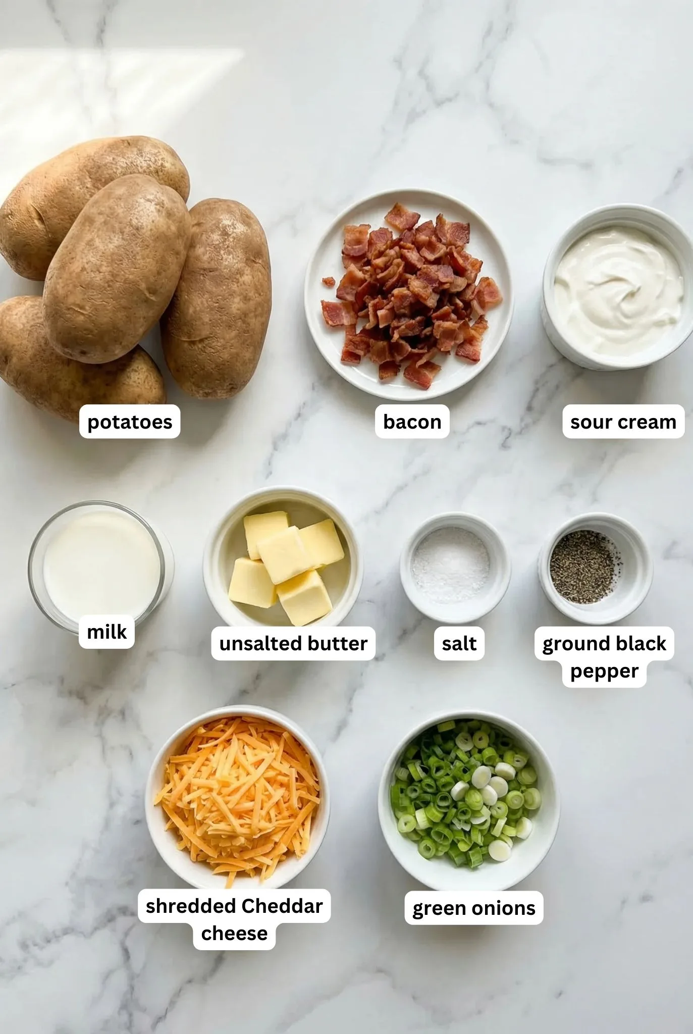 ingredients for Twice Baked Potatoes including potatoes bacon sour cream butter milk cheddar cheese salt pepper and green onions