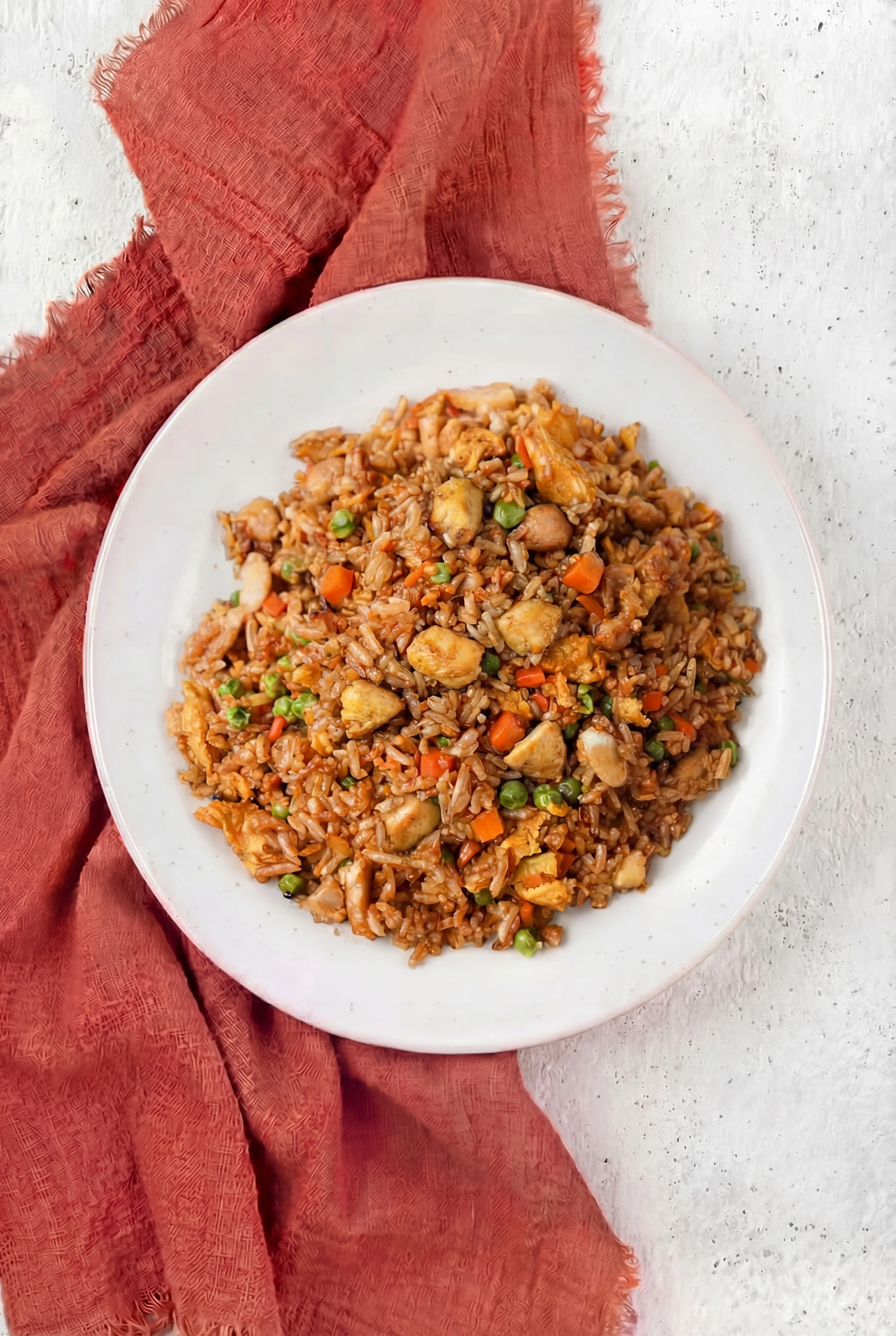 Chicken Fried Rice served in white bowl with diced chicken peas carrots scrambled eggs and seasoned rice