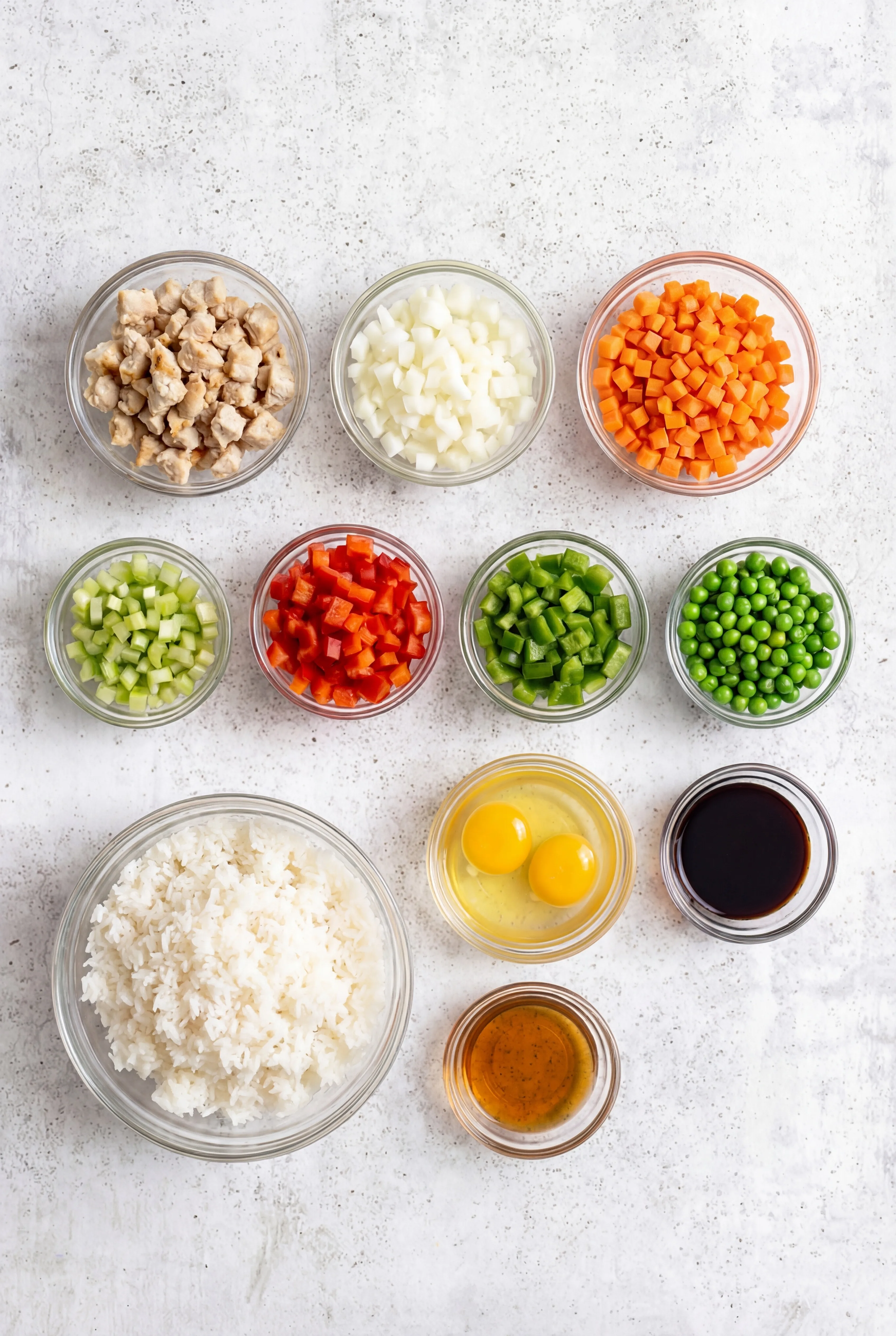 ingredients for Chicken Fried Rice including diced chicken cooked rice eggs soy sauce peas carrots onion and bell peppers