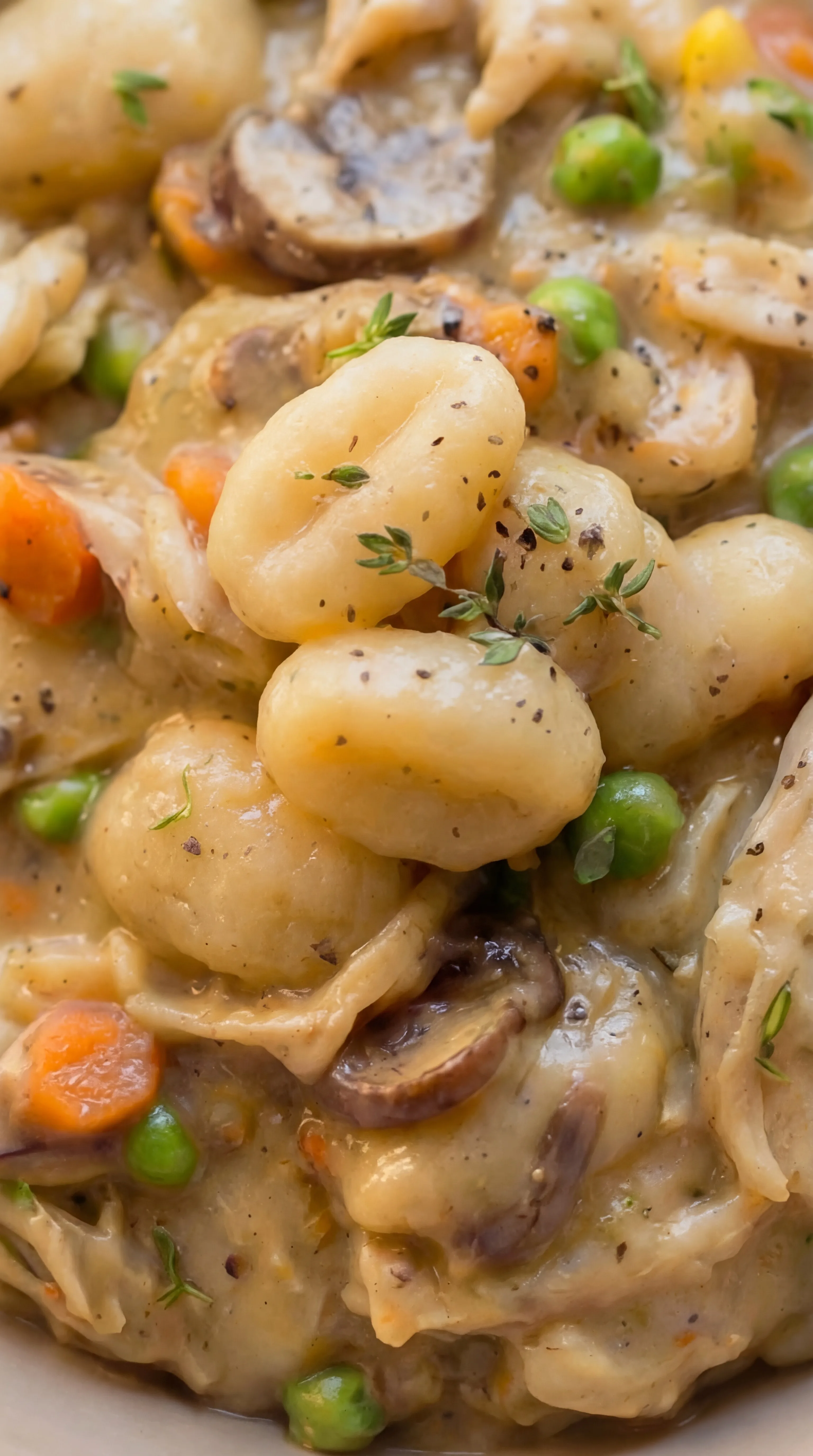 close up of soft gnocchi with shredded chicken mushrooms and peas coated in creamy pot pie sauce