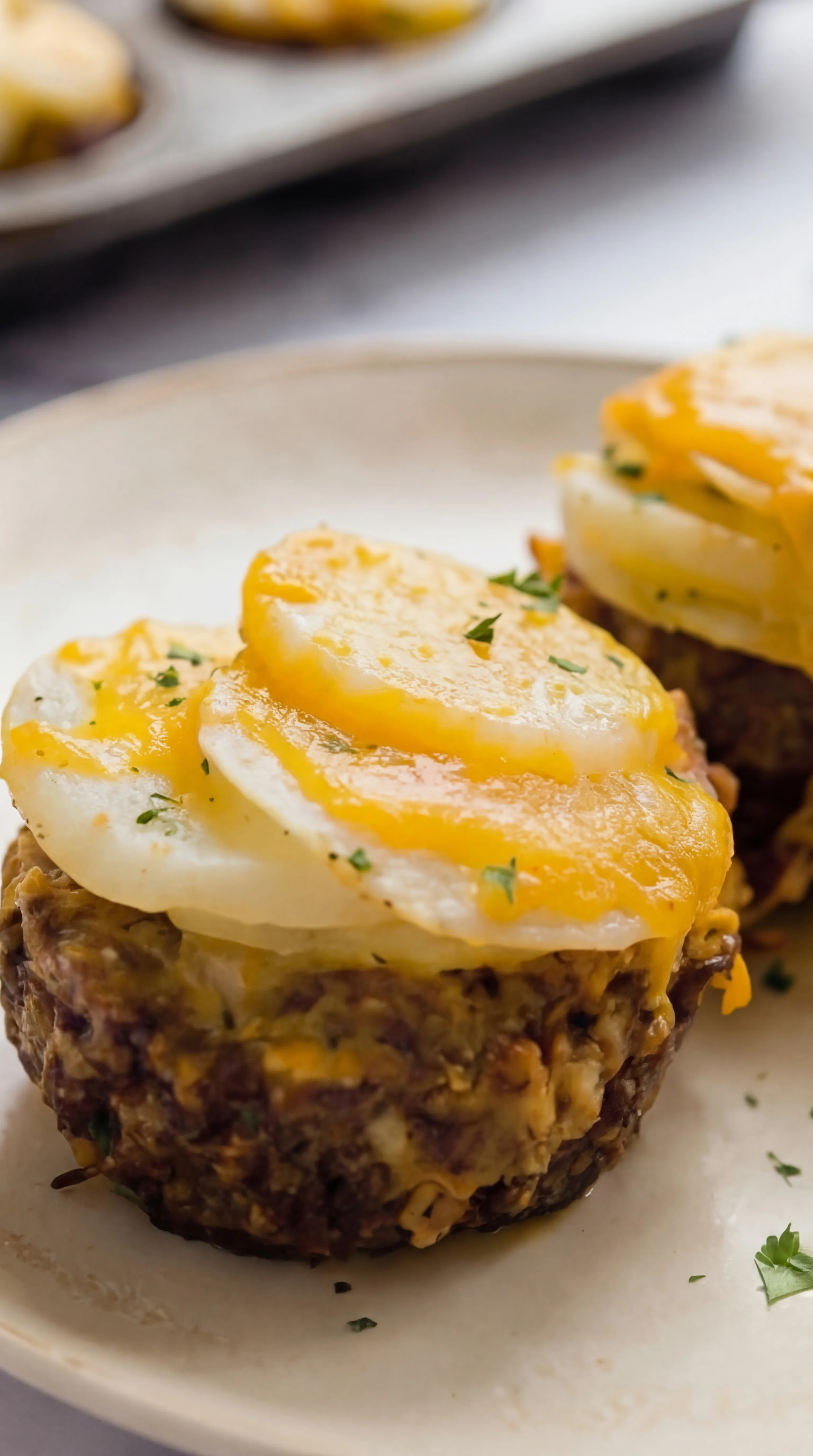 close-up of mini meatloaf topped with tender potato slices and melted cheese garnish