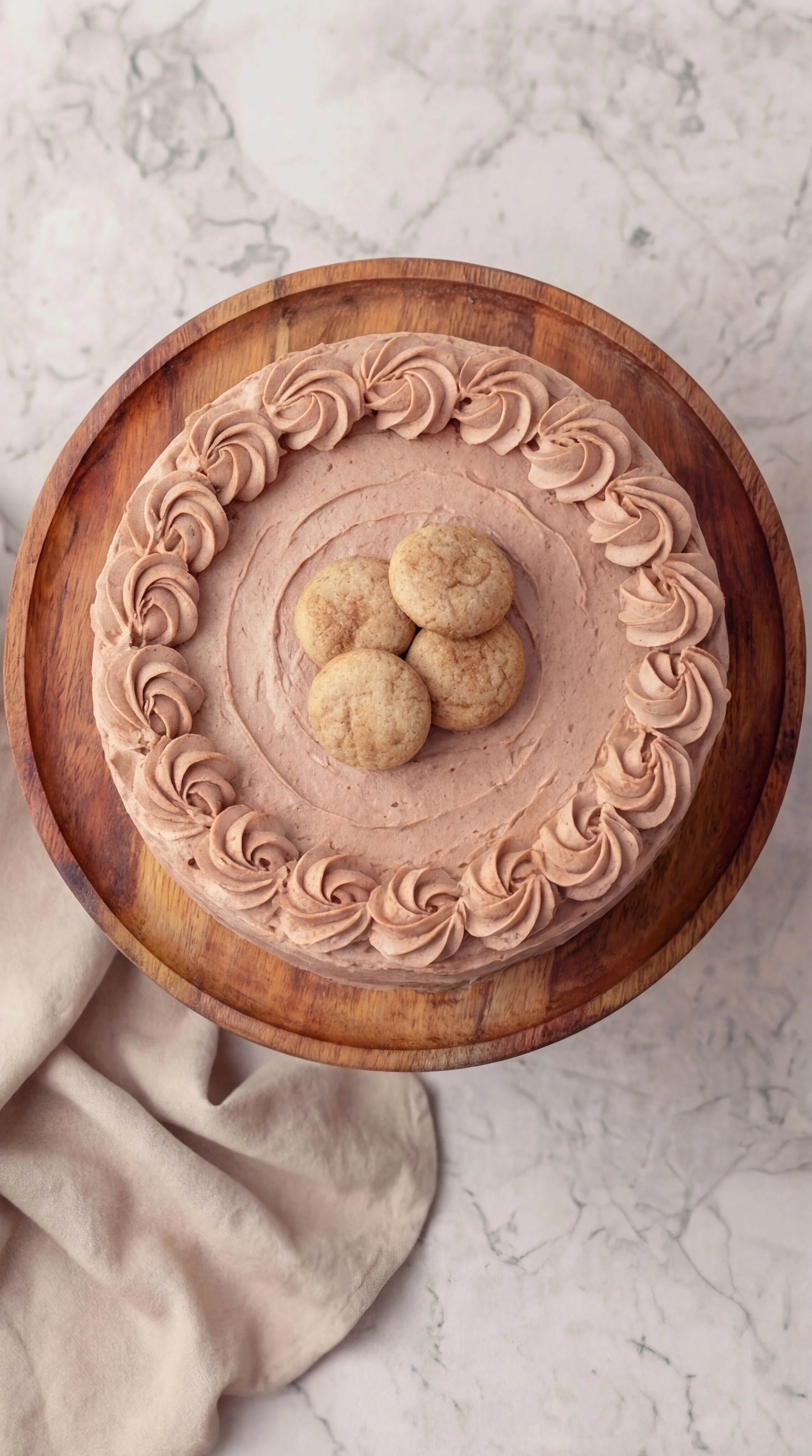 homemade cinnamon frosted cake topped with snickerdoodle cookies and piped buttercream border