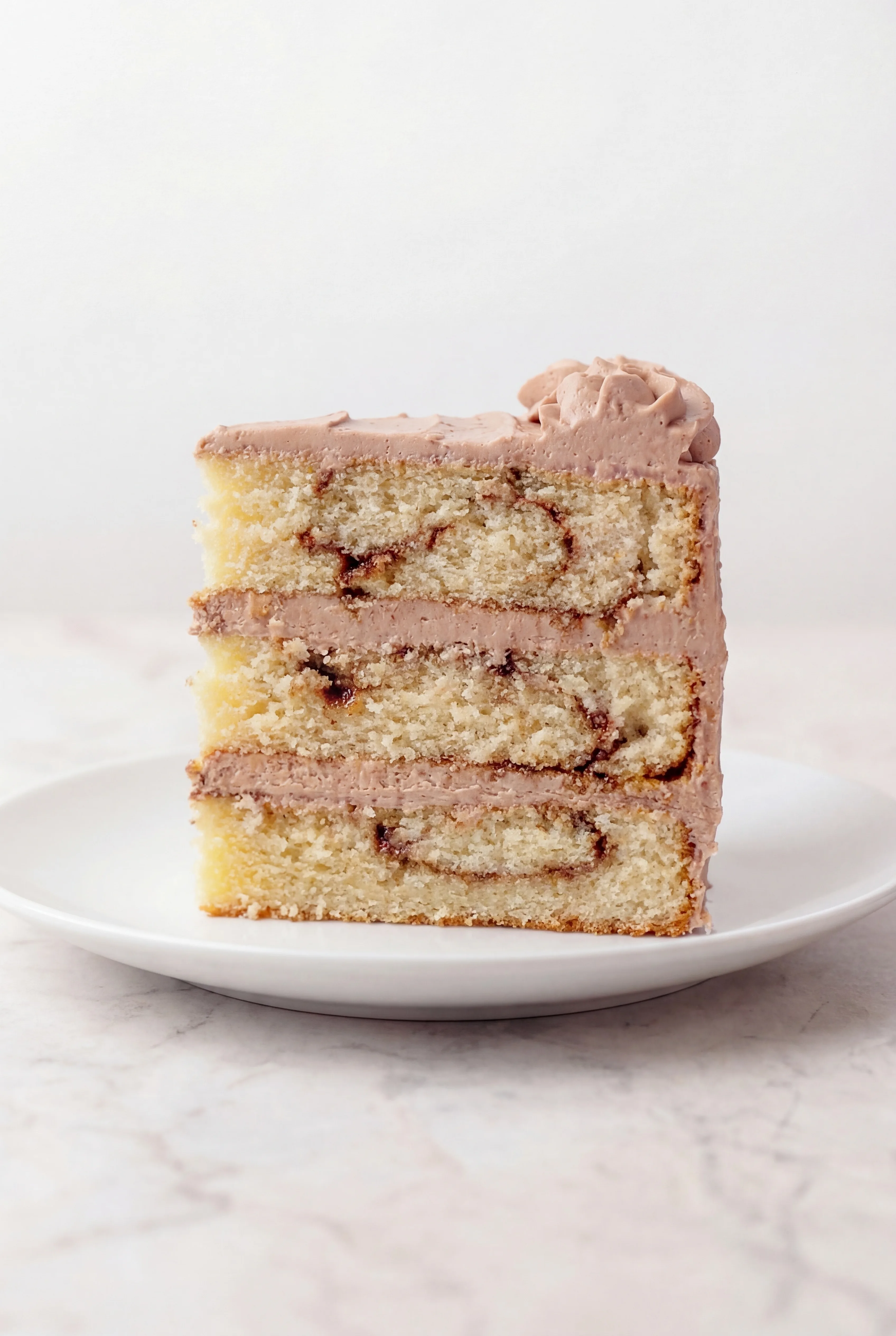 slice of cinnamon swirl layer cake with creamy frosting
